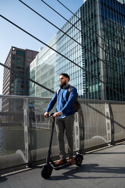 Hombre de tiro completo en scooter eléctrico al aire libre