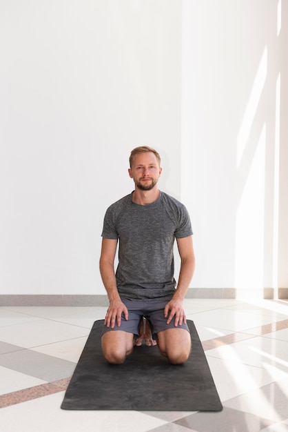 Foto gratuita hombre de tiro completo sentado en la estera de yoga