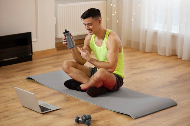 Hombre de tiro completo sentado en la estera de yoga