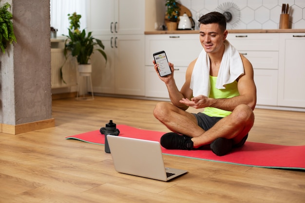 Hombre de tiro completo sentado en la estera de yoga