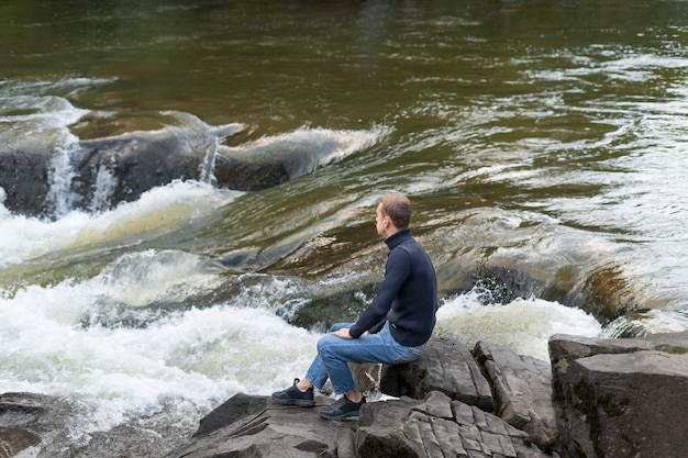 Hombre de tiro completo sentado junto al río