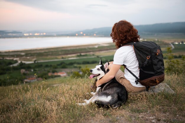 Hombre de tiro completo sentado con perro en la naturaleza