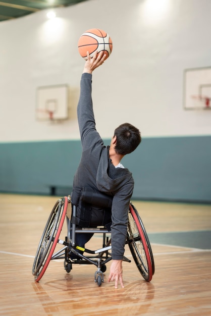 Hombre de tiro completo en silla de ruedas en la cancha de baloncesto