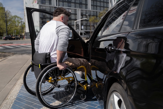 Hombre de tiro completo en silla de ruedas cerca del coche