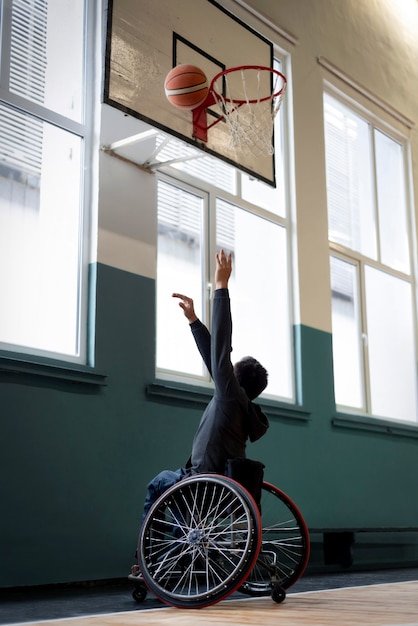 Hombre de tiro completo en silla de ruedas jugando baloncesto