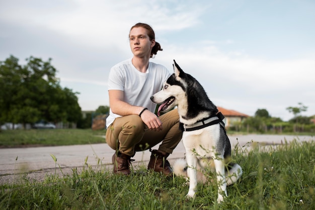 Hombre de tiro completo sosteniendo husky al aire libre