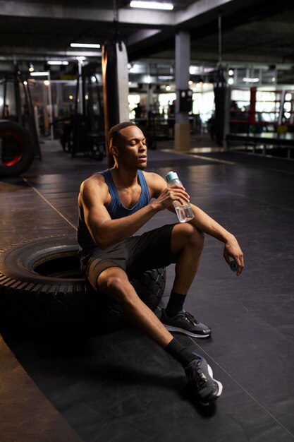 Hombre de tiro completo tomando un descanso en el gimnasio