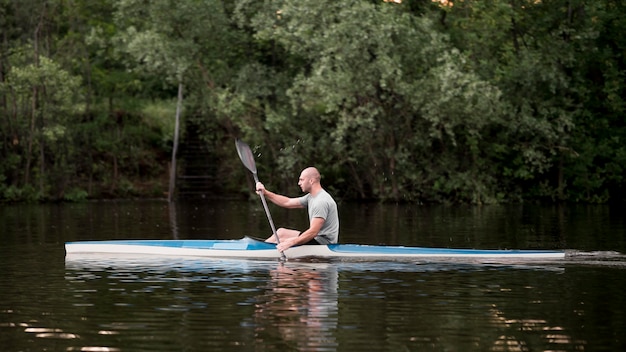 Hombre de tiro largo en kayak con paleta