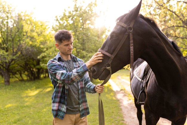 Hombre de tiro medio acariciando a caballo fuera