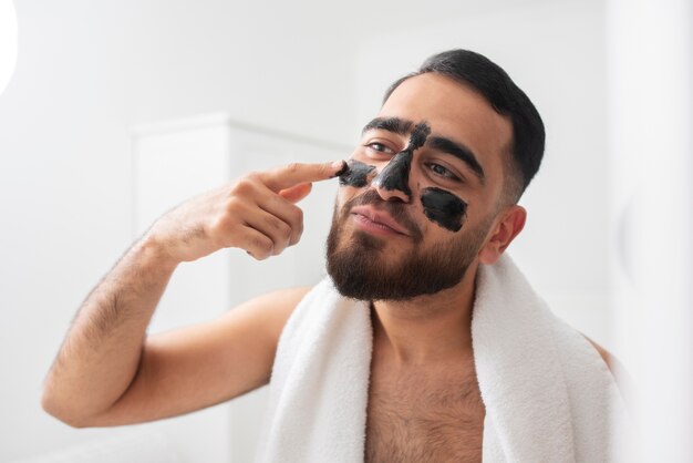 Hombre de tiro medio aplicando tratamiento facial