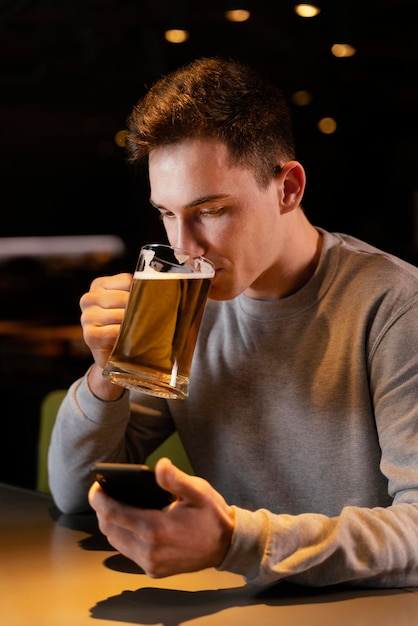 Hombre de tiro medio bebiendo cerveza en el pub