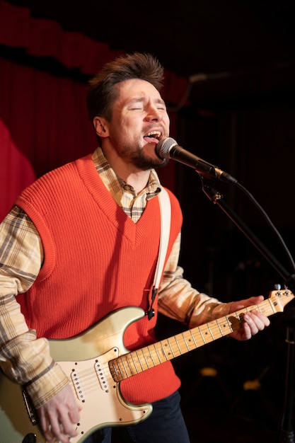 Foto gratuita hombre de tiro medio cantando con micrófono.