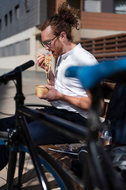 Hombre de tiro medio comiendo en un banco