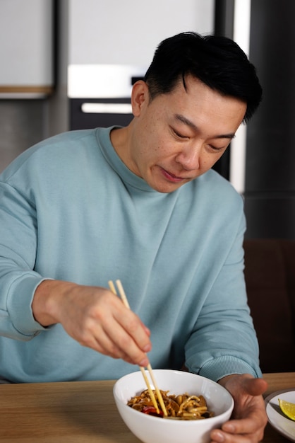 Foto gratuita hombre de tiro medio comiendo comida asiática