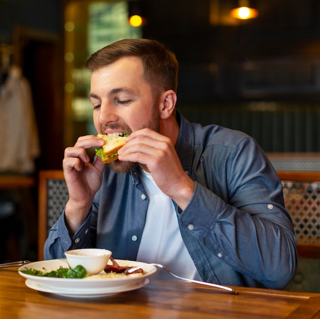 Hombre de tiro medio comiendo en interiores