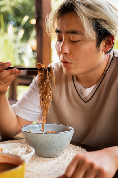 Hombre de tiro medio comiendo con palillos