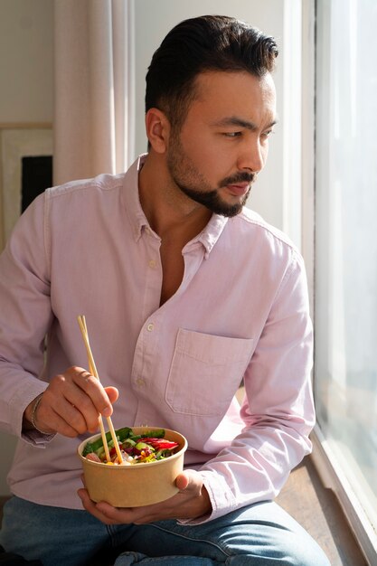 Hombre de tiro medio comiendo un tazón de salmón