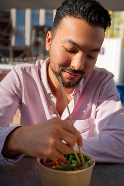 Hombre de tiro medio comiendo un tazón de salmón