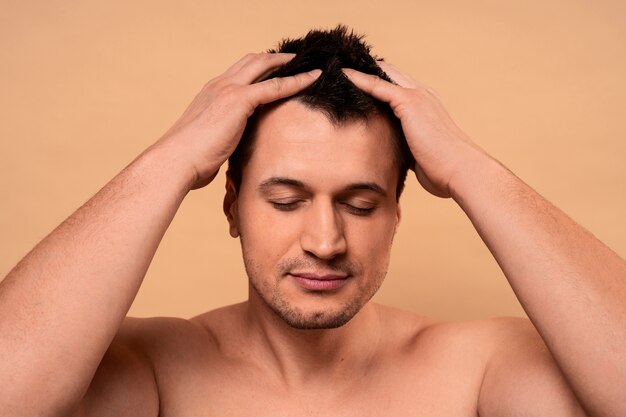 Hombre de tiro medio dándose un masaje en el cuero cabelludo