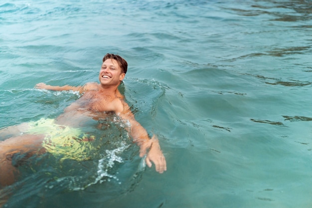 Hombre de tiro medio disfrutando de tiempo en la playa