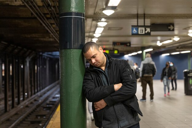 Hombre de tiro medio durmiendo en la estación de metro