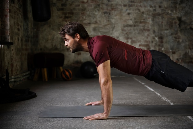 Hombre de tiro medio entrenando con colchoneta de yoga