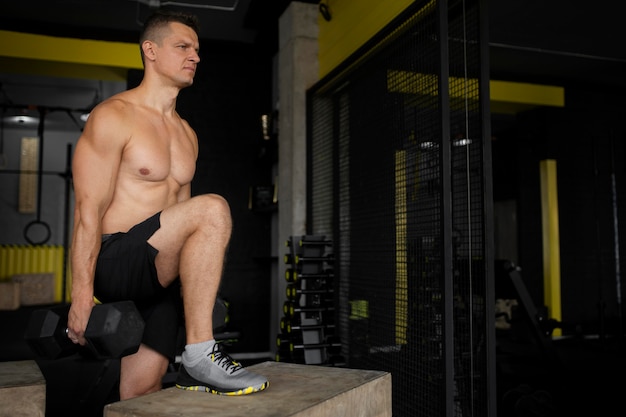 Hombre de tiro medio entrenando con mancuernas