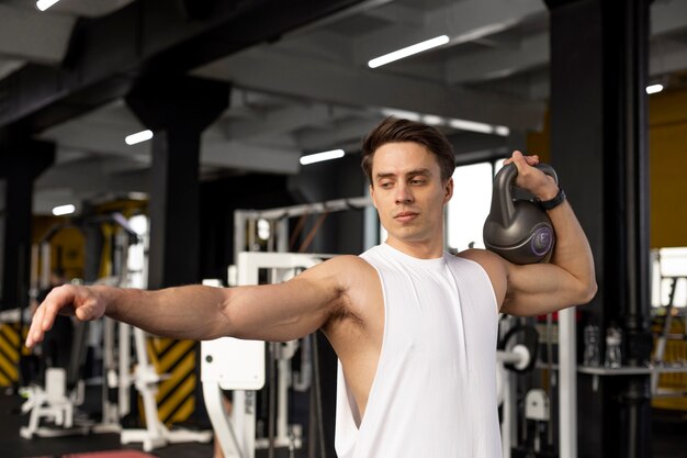 Hombre de tiro medio entrenando con pesas rusas