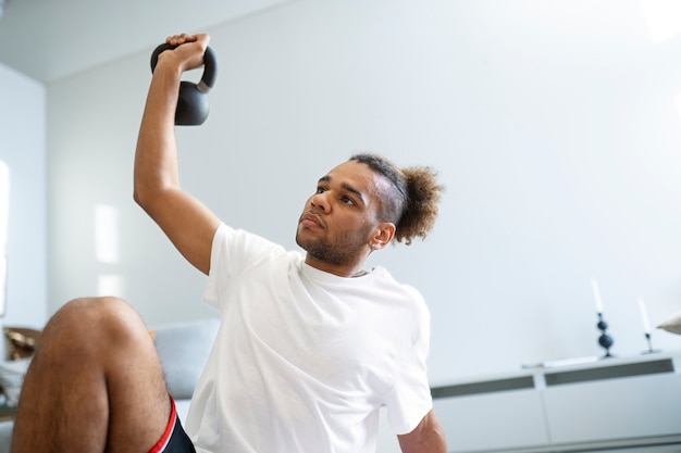 Hombre de tiro medio entrenando con pesas rusas