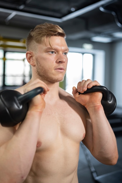 Hombre de tiro medio entrenando con pesas rusas