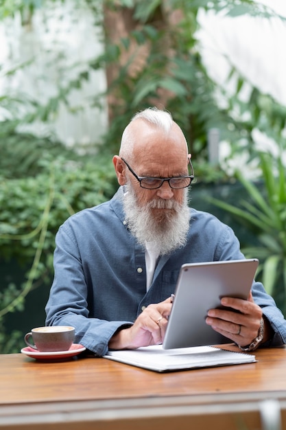 Hombre de tiro medio estudiando con tableta