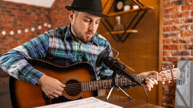 Hombre de tiro medio con guitarra y micrófono