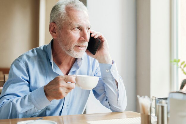 Hombre de tiro medio hablando por teléfono con té