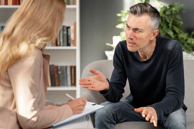 Hombre de tiro medio hablando con terapeuta de mujer