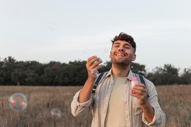 Hombre de tiro medio haciendo globos de jabón