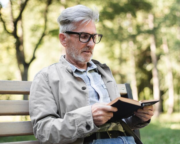 Hombre de tiro medio leyendo al aire libre