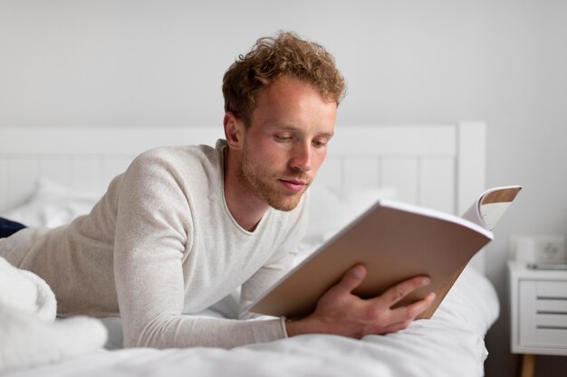 Hombre de tiro medio leyendo en la cama