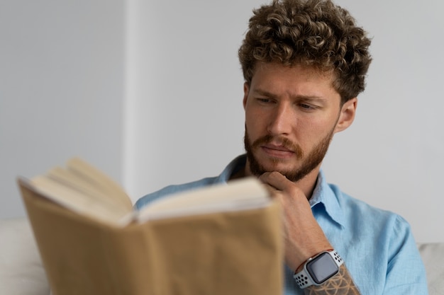 Hombre de tiro medio leyendo en casa