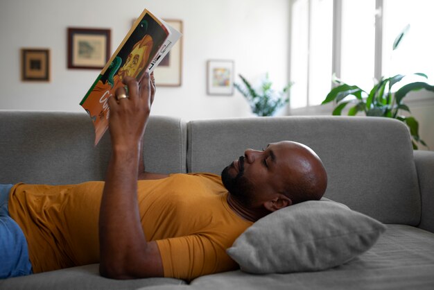 Hombre de tiro medio leyendo cómics en casa