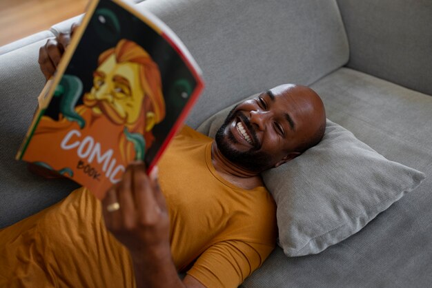 Hombre de tiro medio leyendo cómics en casa