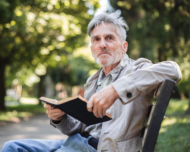 Hombre de tiro medio con libro al aire libre