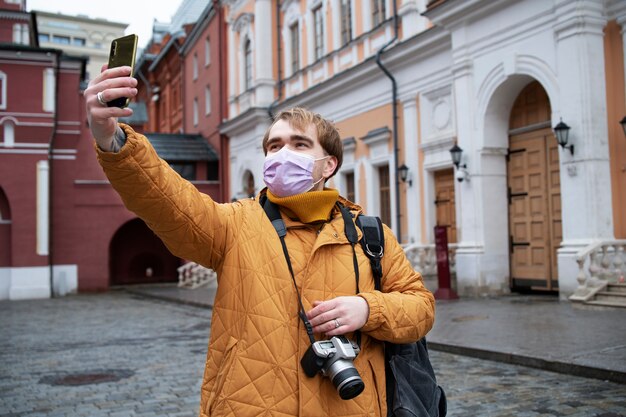 Hombre de tiro medio con máscara tomando selfie
