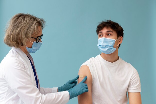 Hombre de tiro medio con máscara vacunándose