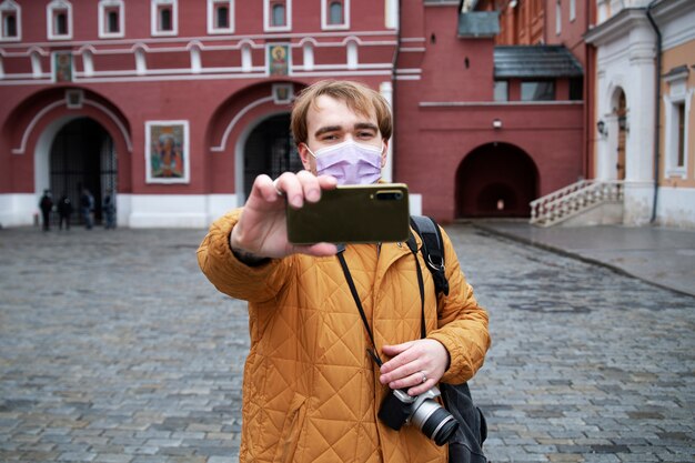 Hombre de tiro medio con mascarilla tomando selfie