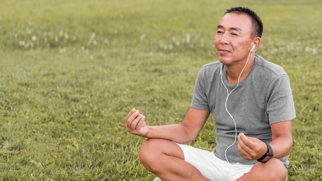 Hombre de tiro medio meditando sobre el césped