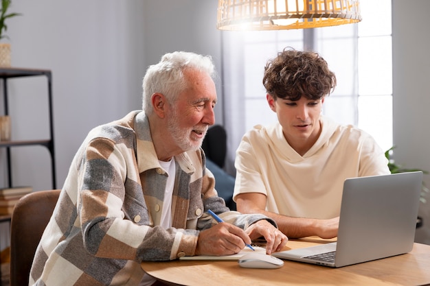 Hombre de tiro medio y nieto con computadora portátil