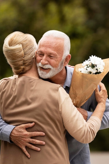 Hombre de tiro medio ofreciendo flores a la mujer