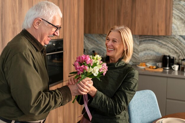 Hombre de tiro medio ofreciendo flores a mujer.