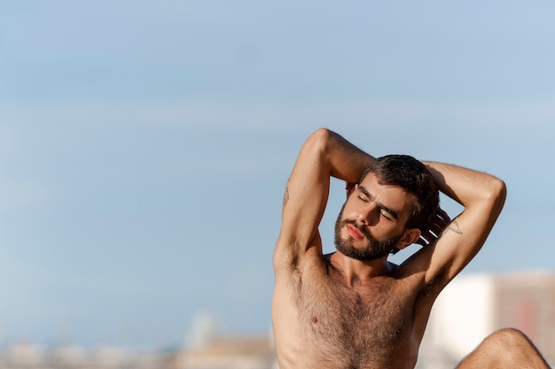 Foto gratuita hombre de tiro medio con pecho peludo en la playa.