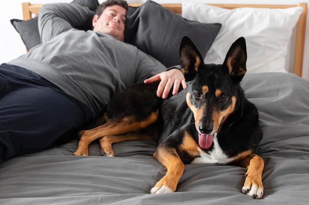 Foto gratuita hombre de tiro medio con perro en la cama